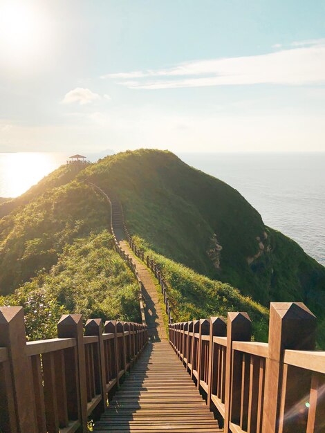 Photo footbridge leading towards mountains by sea against sky