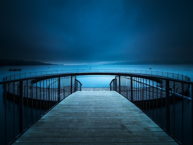 footbridge over sea against sky at night