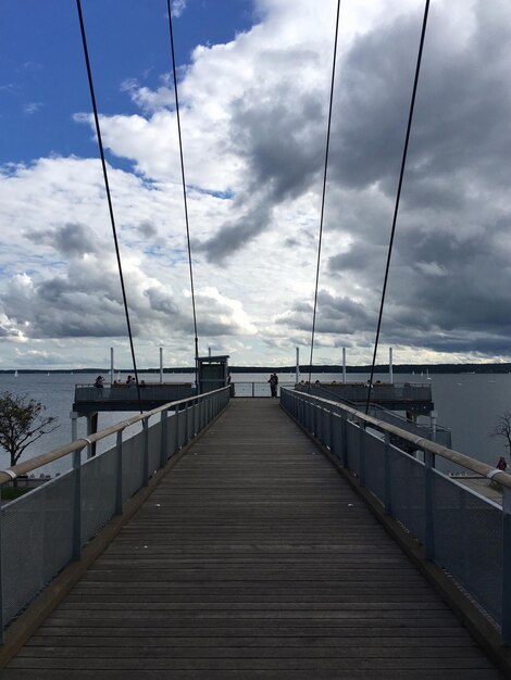 Footbridge over sea against sky