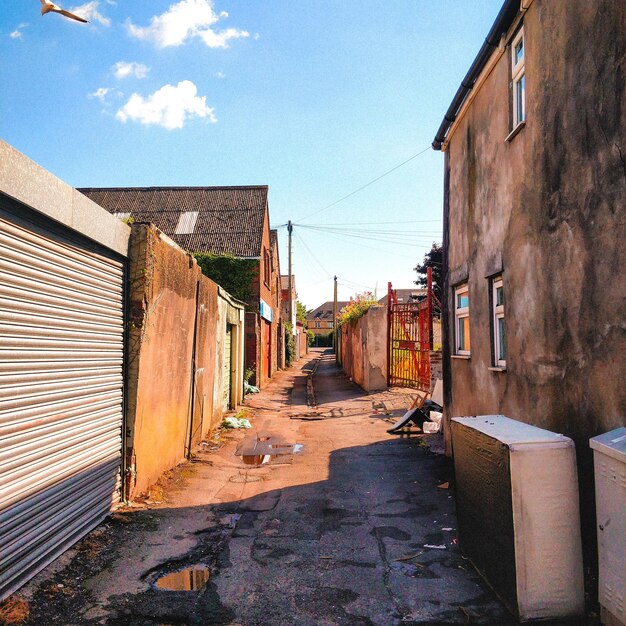 Photo footpath amidst buildings against sky lane alley garage vanishing point alleyway brick wall