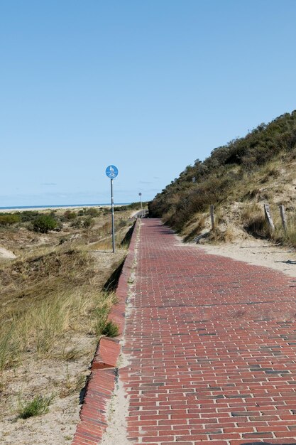 Footpath by road against clear blue sky