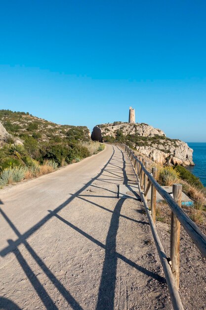 Footpath by sea against clear blue sky