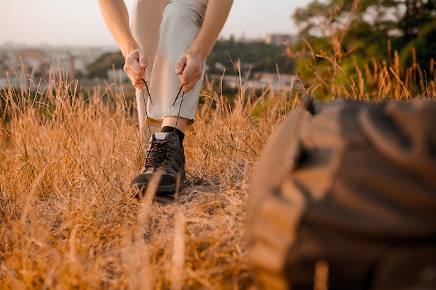 On the footpath. Close up picture of mans hands lacing the boots