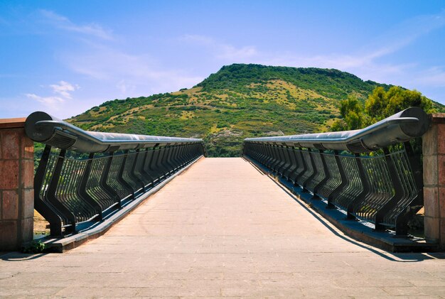 Footpath leading towards mountains against sky