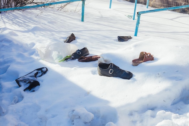 Foto impronte di piedi e vecchie scarpe sulla neve bianca pura in una fredda giornata di sole sullo sfondo sfocato