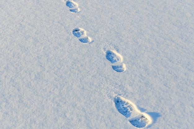 白い雪の上の靴底の足跡