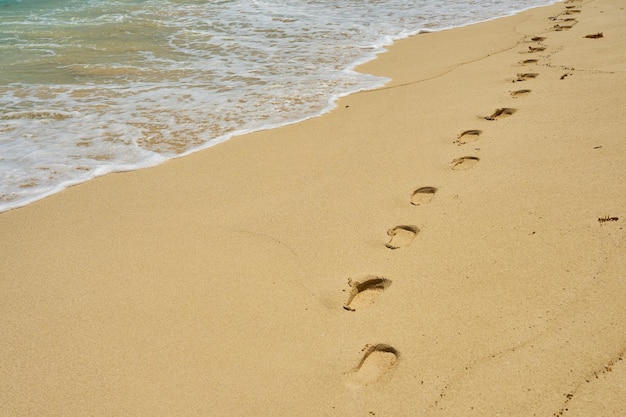 Footprints and waves with foam on the Caribbean coast in Mexico