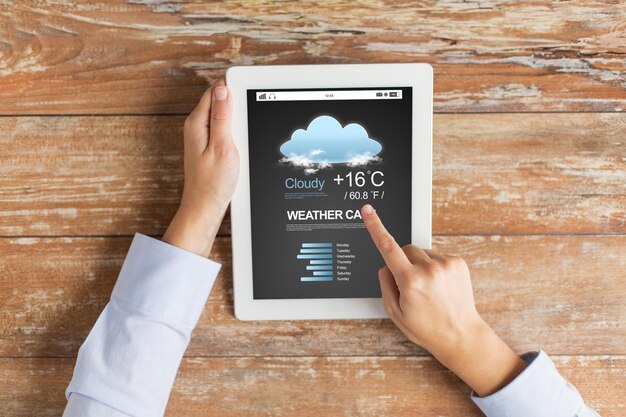forecast, meteorology, people and technology concept - close up of female hands with weather cast on tablet pc computer screen