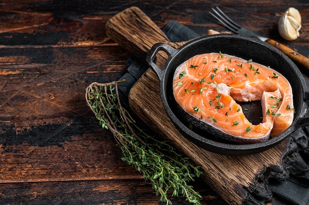 Forel of zalm rauwe steaks in een pan met tijm. Donkere houten achtergrond. Bovenaanzicht. Ruimte kopiëren.