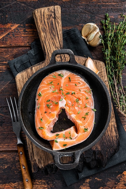 Forel of zalm rauwe steaks in een pan met tijm. Donkere houten achtergrond. Bovenaanzicht.