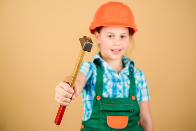 Foreman inspector. Little girl in helmet with hammer. Kid worker in hard hat. Labor day. 1 may. repair shop. hammer in hand of small girl repairing in workshop. Mechanic at work.