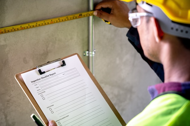 Foreman with documents measuring a wall