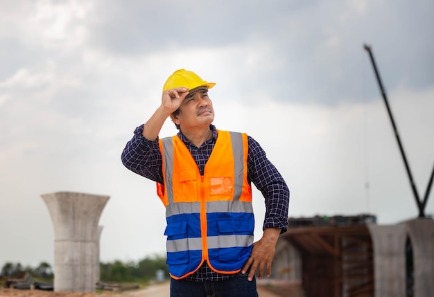 Foreman worker in hardhat at the infrastructure construction\
site asian construction engineer checking project at the building\
site