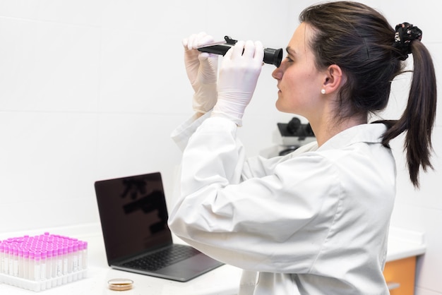 Photo forensic laboratory worker studying samples with refractometer and microscope