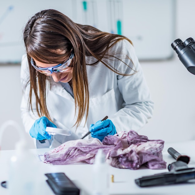 Forensic science expert examining traces of blood on a piece of cloth collected at a crime scene