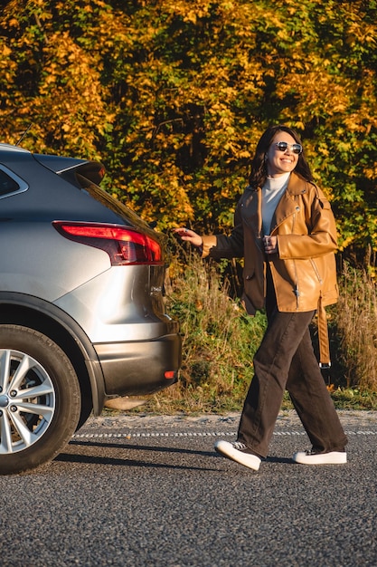 On forest background happy woman walks next to her car