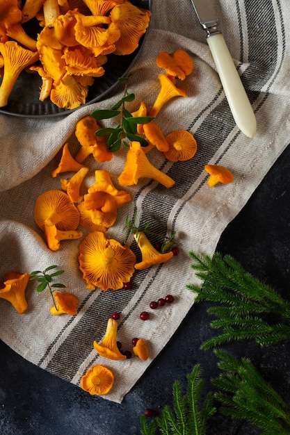 Forest Mushrooms chanterelles and forest moss on a wooden old background. Raw uncooked in rattan plate bowl over brown texture background. Mock up. Top view.