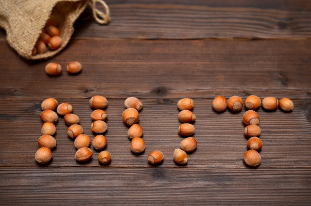 Forest nuts laid out in the word walnut on a wooden background