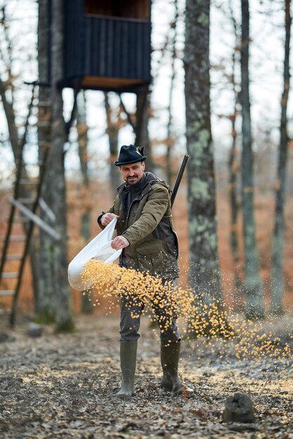 Forest ranger at the game feeding spot spilling maize on the\
ground