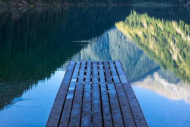 a forest scene and a wooden pier on a mountain lake Kolsai Lake in Kazakhstan