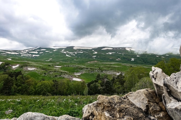 高山の牧草地を見下ろす岩のそばに立つ森アディゲ共和国のLagoNaki高原2021年
