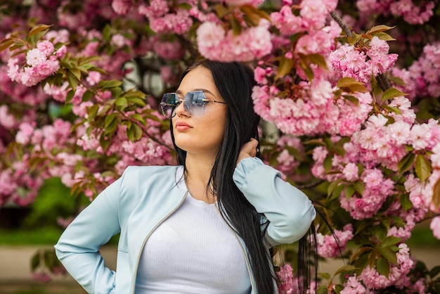 Foto per sempre giovani. vacanze di primavera. fiore di ciliegio. la ragazza sexy gode del fiore di sakura. donna in fiore di ciliegio. stile di bellezza e moda. donna nel parco con fiori di alberi rosa. sakura sta sbocciando.