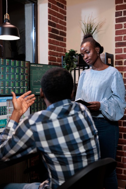 Forex stock market professional traders in office workspace discussing about bearish market trend. Financial company employees analyzing real time charts while monitoring open trades.