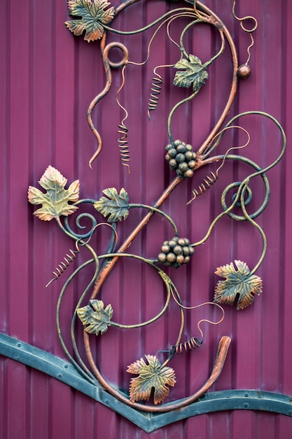 Photo forged bunch of grapes. ornate wrought-iron elements of metal gate decoration.