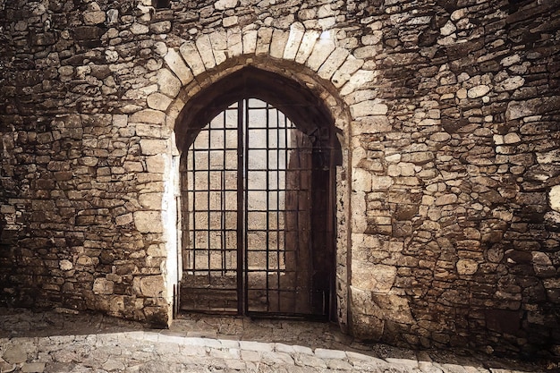 Forged metal medieval door in arched stone wall