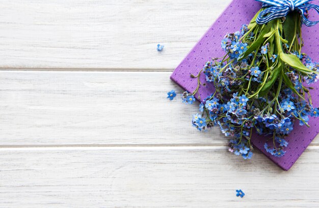 Forget-me-not flowers and notebook on a white wooden table