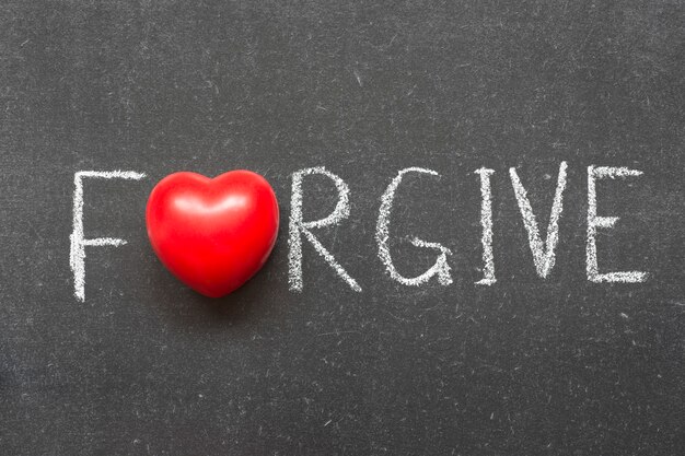 Forgive word handwritten on chalkboard with heart symbol instead of O