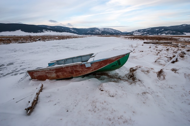 Forgotten boat frozen in ice on the river