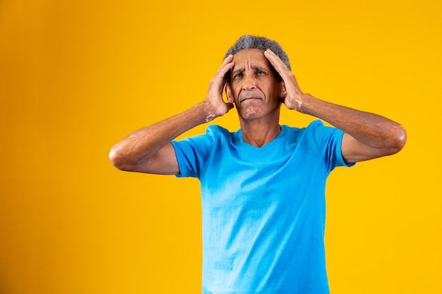Forgotten and confused elderly afro man on yellow background
