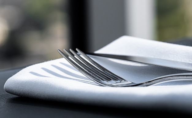 Fork and knife with white napkin on table in luxury restaurant outdoors fine dining menu for wedding...