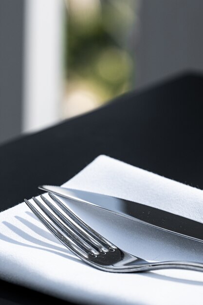 Forchetta e coltello con tovagliolo bianco sul tavolo in un ristorante di lusso all'aperto menu raffinato per matrimoni...