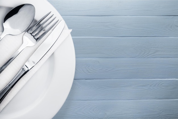 Fork, spoon and knife on plate on wooden background