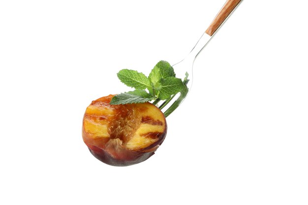 Fork with grilled peach isolated on white background