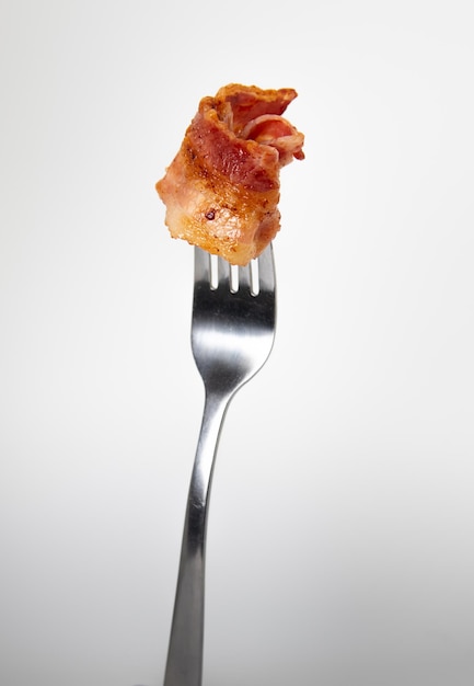 A fork with a piece of bacon on it