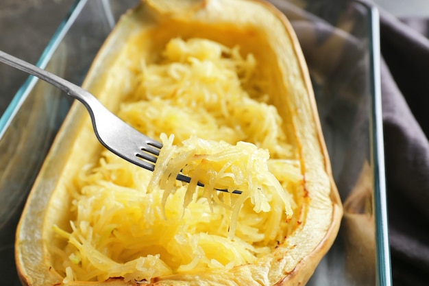 Fork with spaghetti squash over baking dish close up