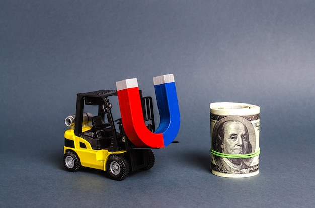 A forklift carries a magnet to a bundle of dollars Attracting money and investments for business