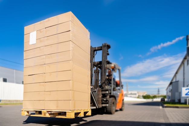 Forklift vehicle manipulating goods in logistic area outside warehouse.