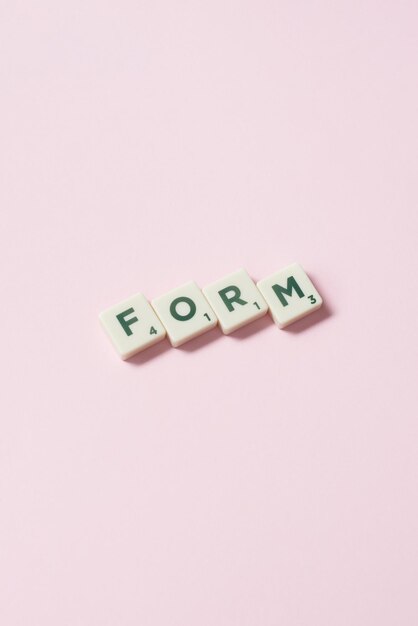 Form formed of scrabble tiles on pink background