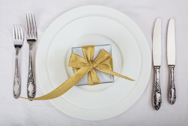 Formal table setting and a gift on white background