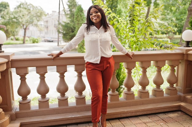 Donna di affari dell'afroamericano formalmente vestita in camicetta bianca e pantaloni rossi. imprenditrice di successo dalla pelle scura.
