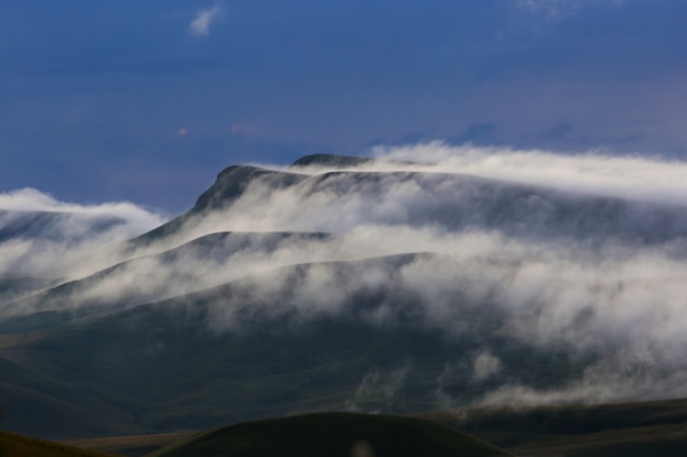 The formation of fog and clouds during sunset over the mountains.