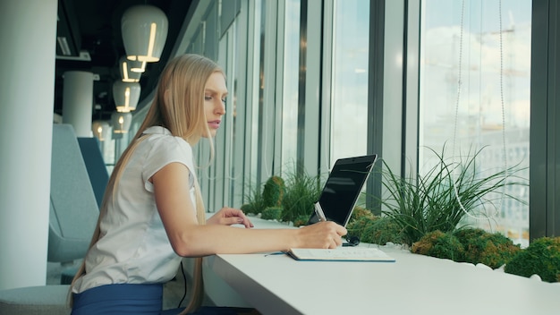 Formele vrouw met laptop en papieren.