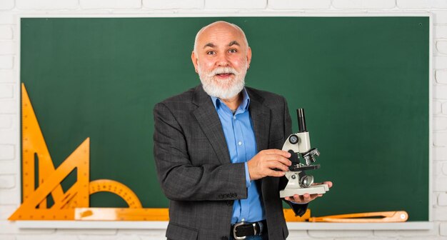 Formule chemie in school wetenschap experimenten met Microscoop in lab Biologie school laboratorium apparatuur man in klas met wiskundige tools op blackboard senior leraar gebruik Microscoop