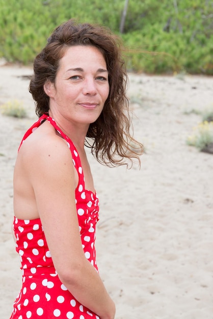 A forties middle aged woman stands on a beach