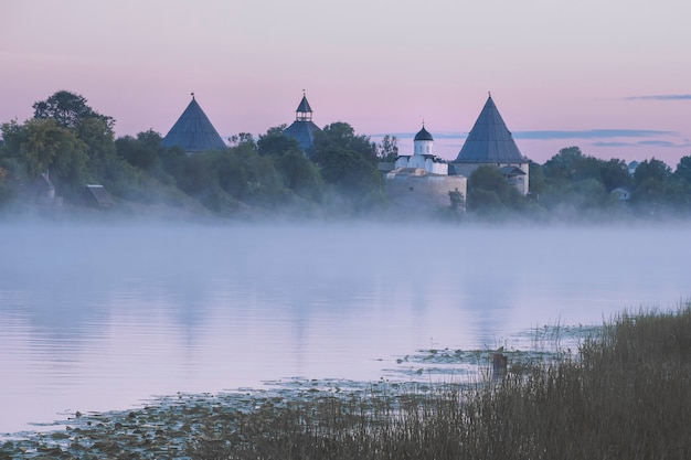 Fortezza nella città di staraya ladoga sul fiume volkhov con un'alba estiva rosa nebbiosa, vecchia architettura nel paesaggio del nord russo