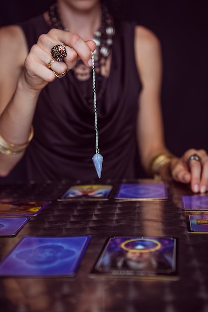 Fortune teller forecasting the future with pendulum on black background